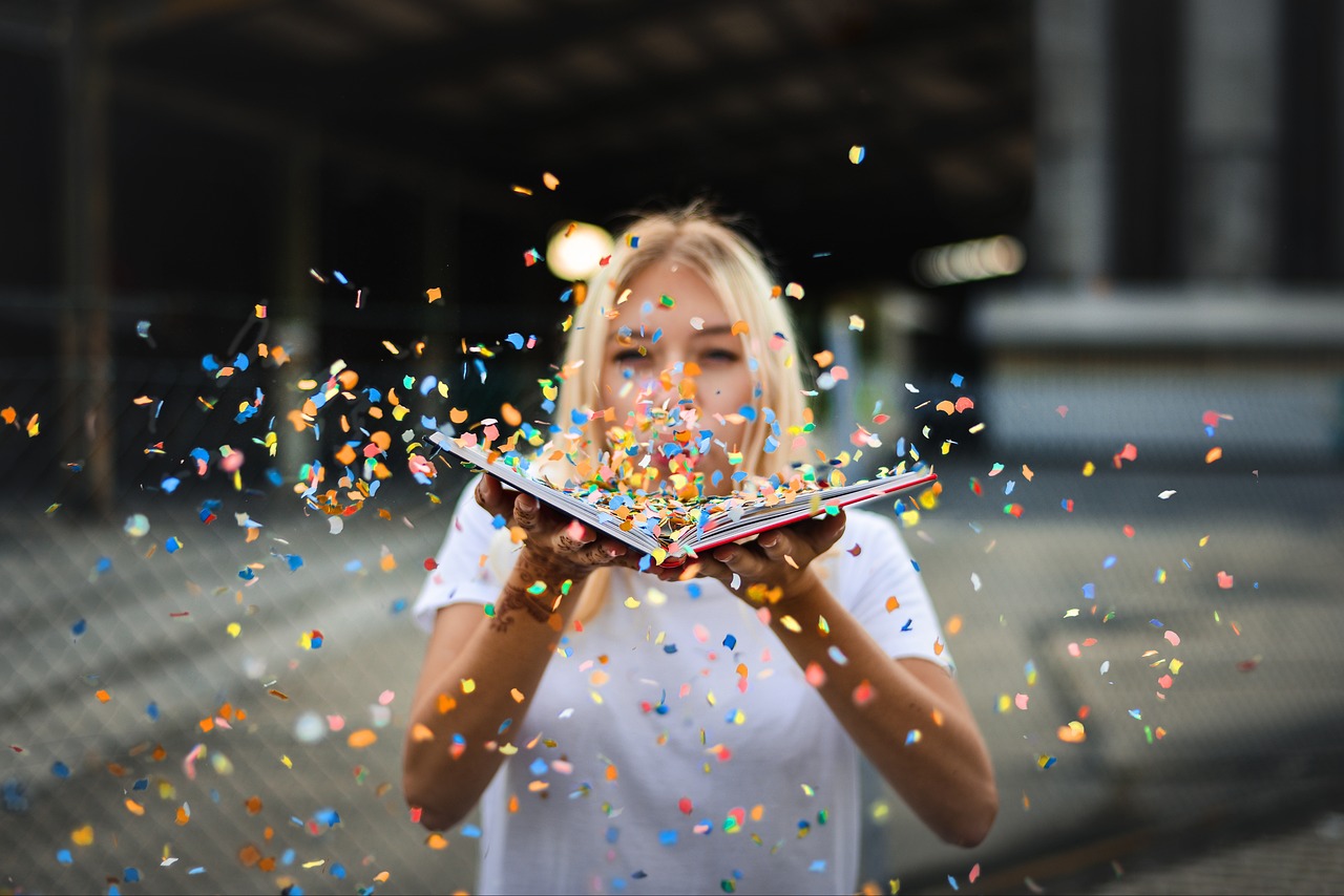 Woman blowing confetti over an open book